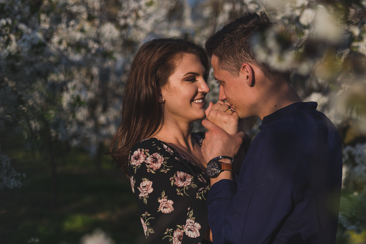 Zdjęcie usmiechniętych narzeczonych w kwitnącym sadzie w wykonaniu - Michał Mercik Fotografia.